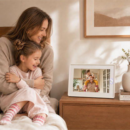 An AmivoFrame smart photo frame displaying a family photo on a minimalist wooden desk with a notebook and desk lamp.